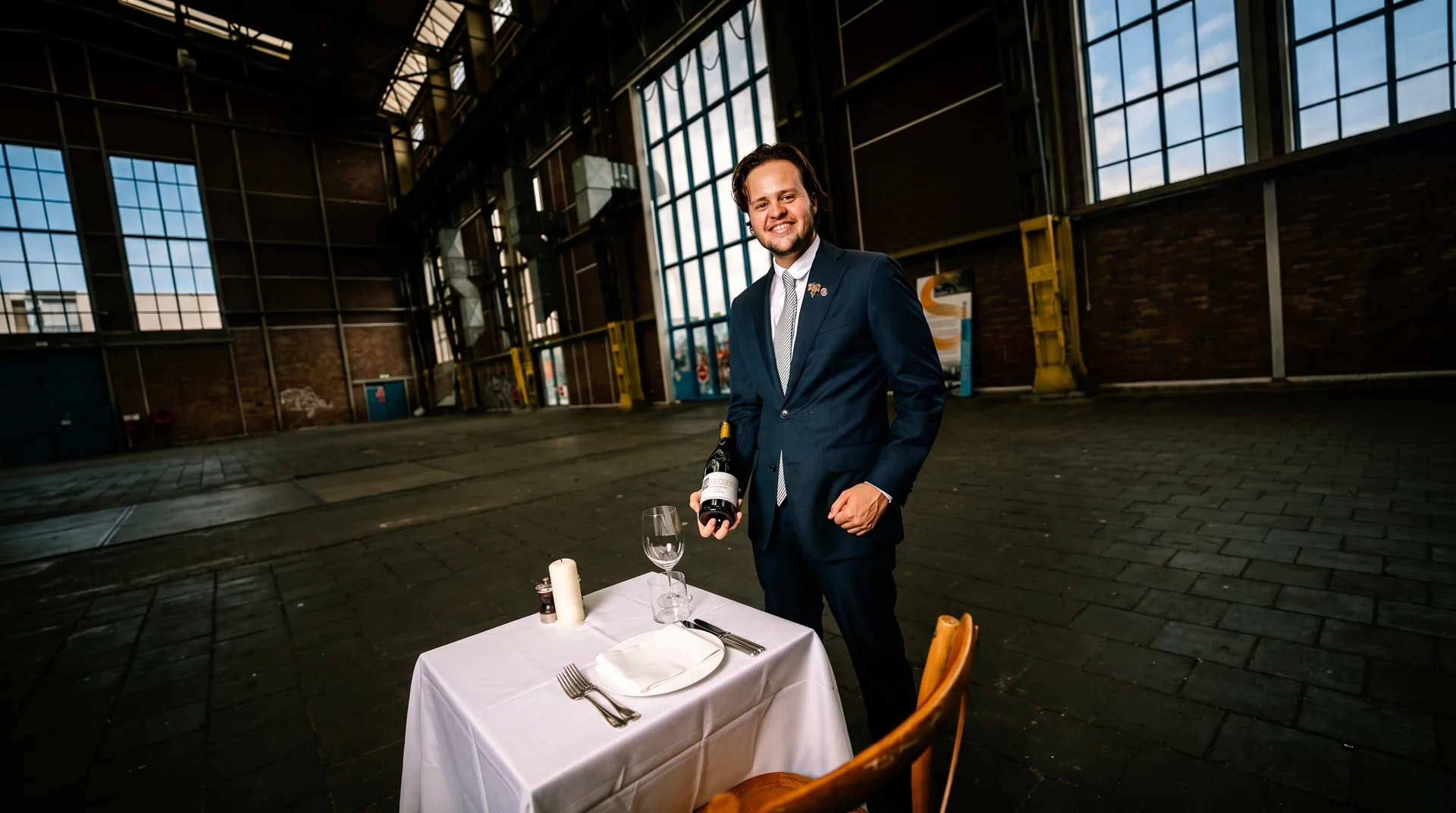 Sommelier met een fles wijn in een industriële hal